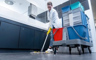 A woman mopping a bathroom floor for a business who have contract cleaning services with efficient KPIs.