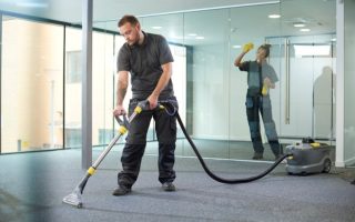 A man hoovering and a woman wiping glass walls, using AI tools and software to reduce subjectivity in quality inspections.