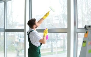 A man cleaning an office window who works for a commercial cleaning company.